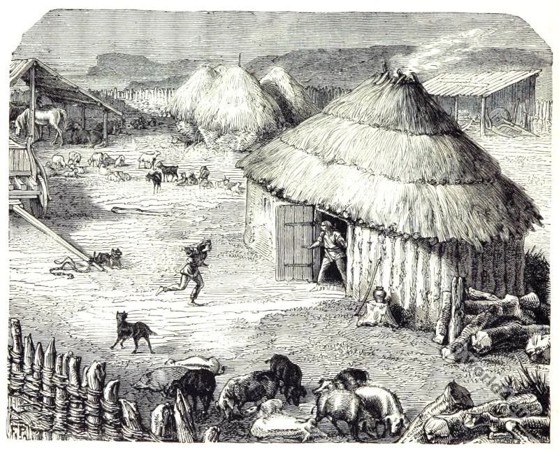 Artistic rendering of a Celtic settlement enclosed by log fencing. Many huts with thatched roofs are visible, with one in the foreground where smoke pours from the top; a person opens the door to the hut to witness a child running in the yard. The yard includes various animals including dogs, pigs, sheep, and horses.